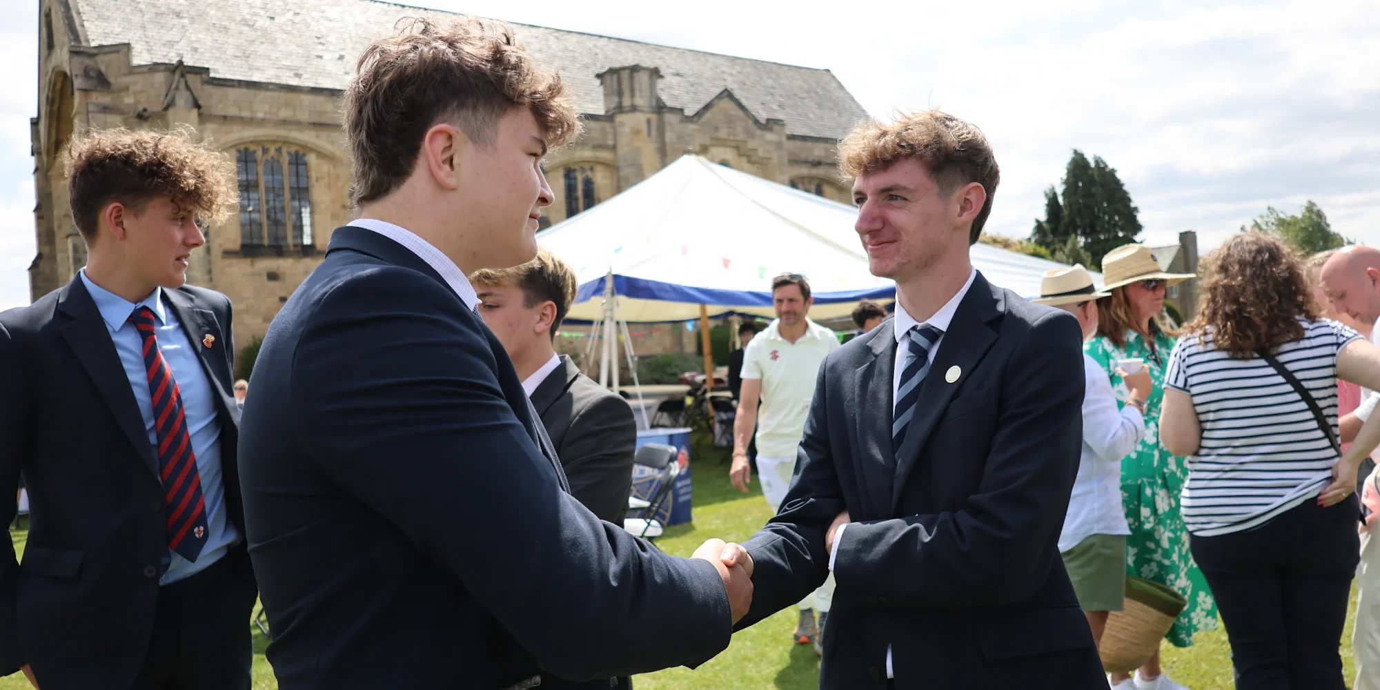 Two students shake hands during a conversation outside of the school.