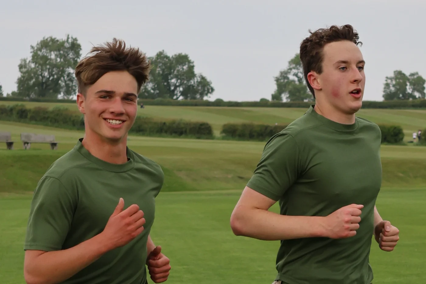 Two students running in field.