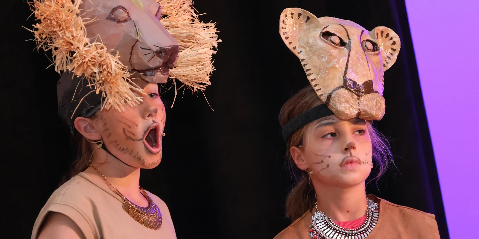 Two girls on stage dressed as lions and singing.