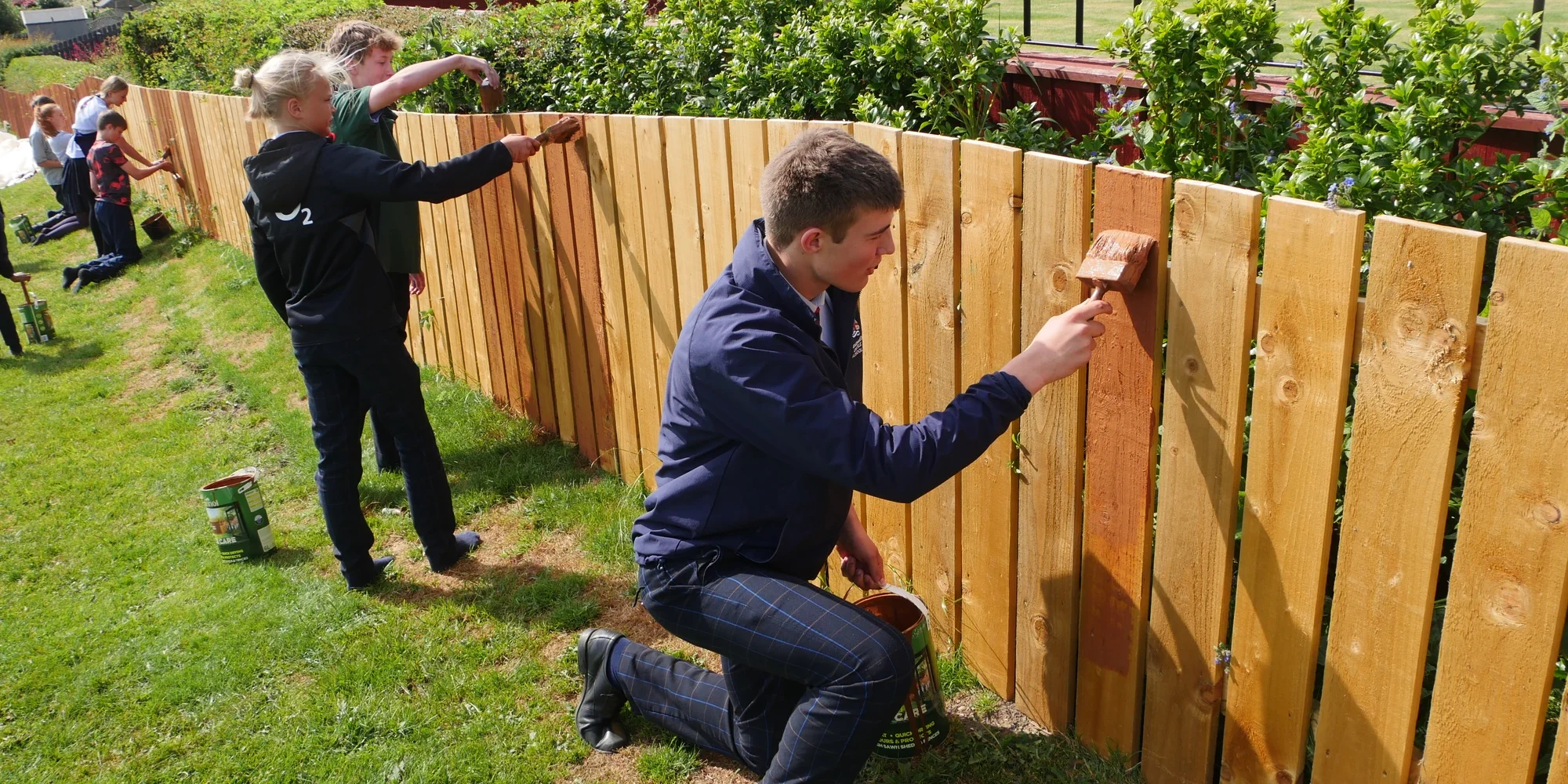 Students painting fence.