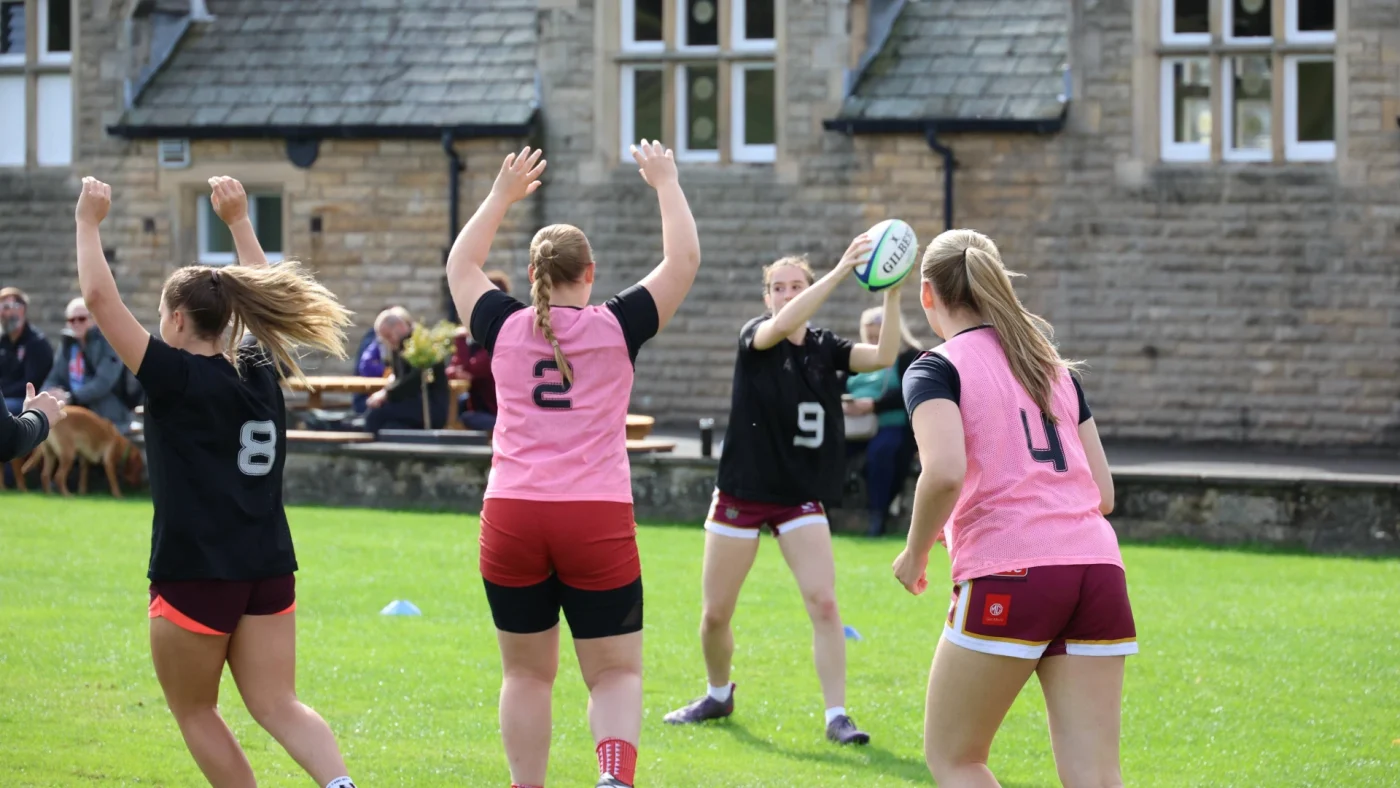 A group of female students playing rugby on the Barney sports field