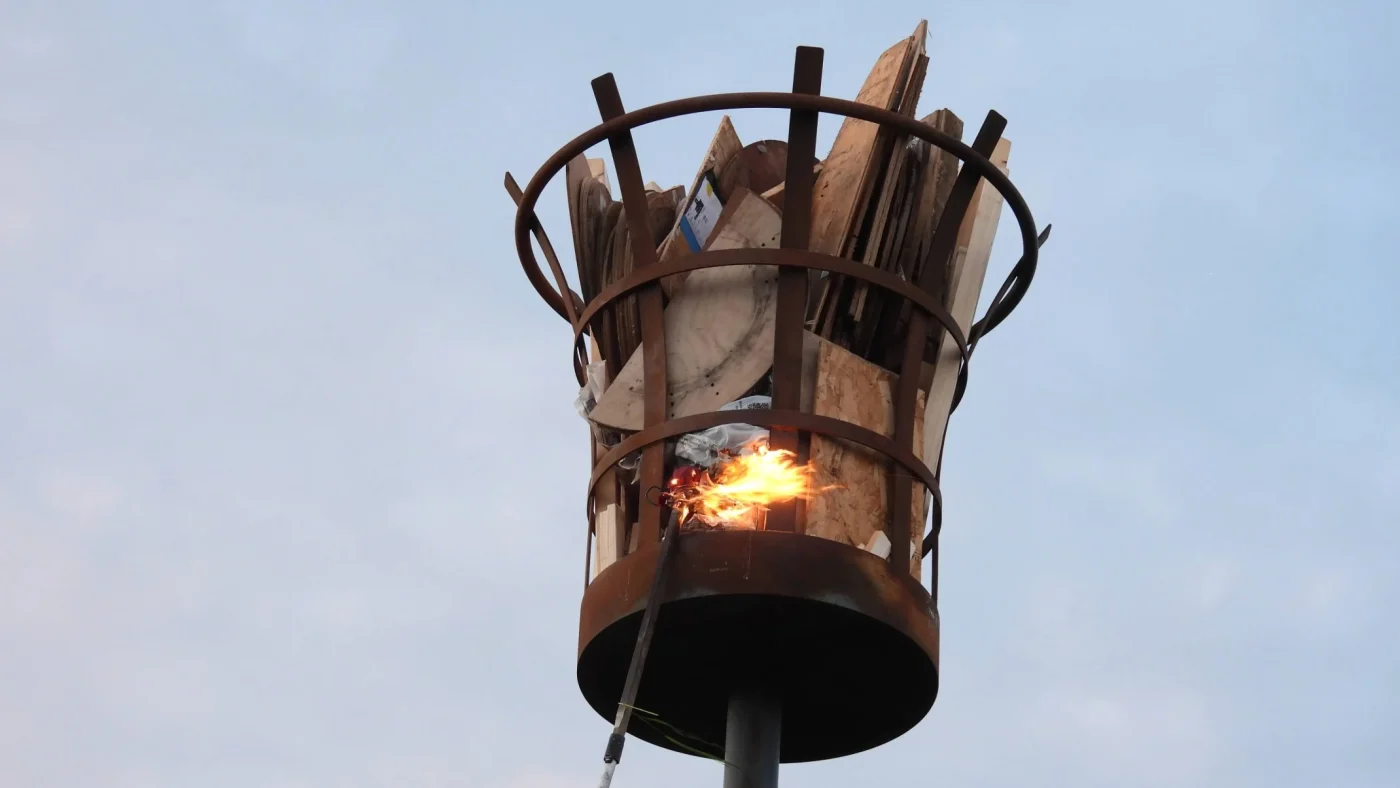 A burning beacon set against a dim blue sky.