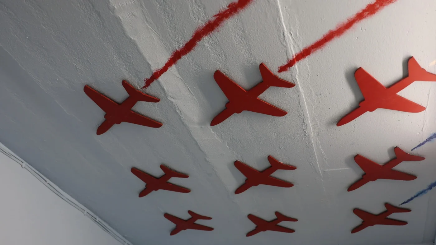 A ceiling display featuring red planes trailing across it.