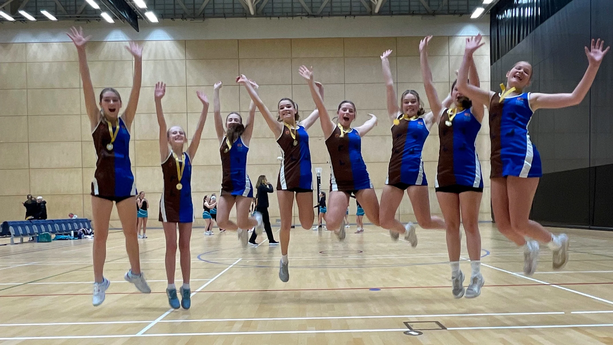 Barney's U14 netball team jumping in a line.