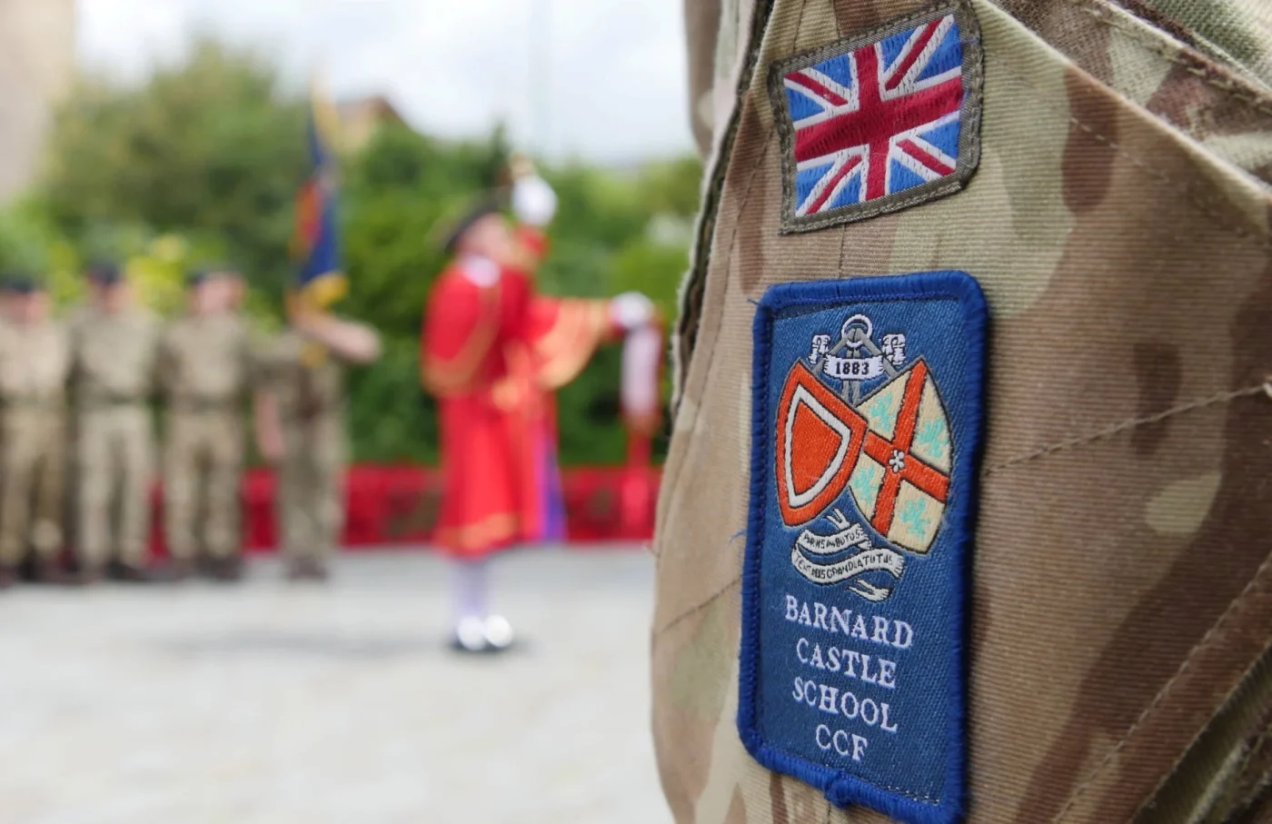 Barnard Castle School badge close up with military personnel